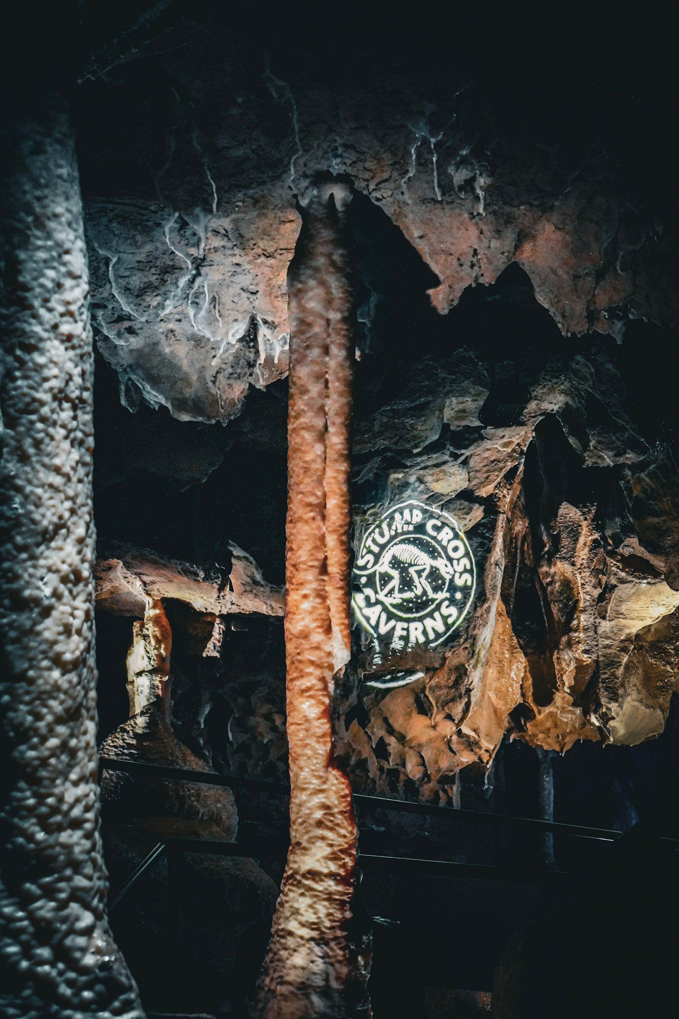 Dimly lit cave interior with rough tan rock walls and a sandy floor