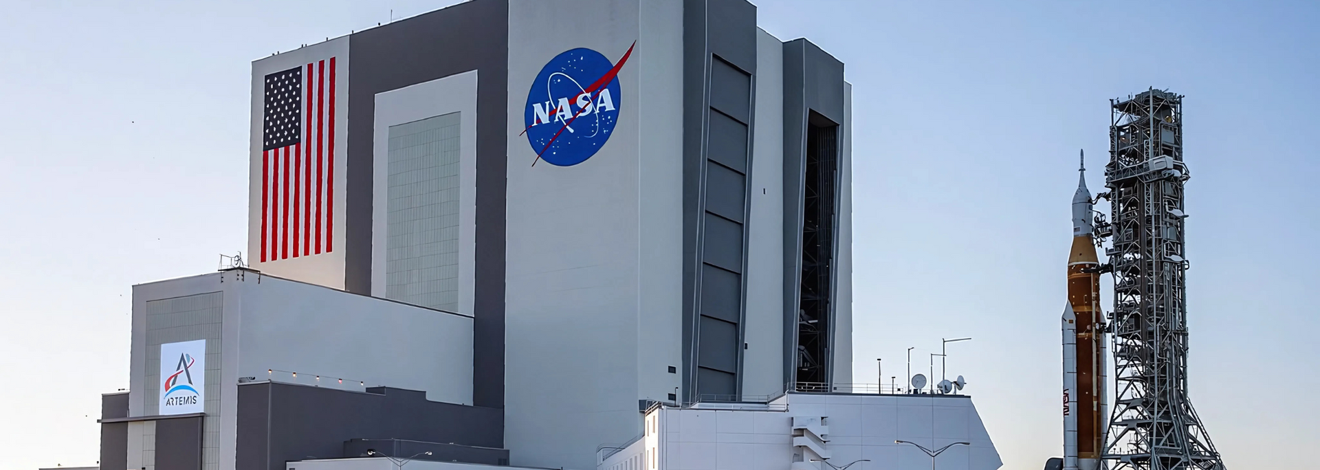 NASA's launch structure with American flag and rocket. NASA logo visible.