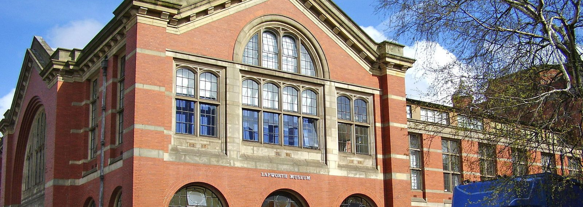 Red brick building with arched windows, under a blue sky.