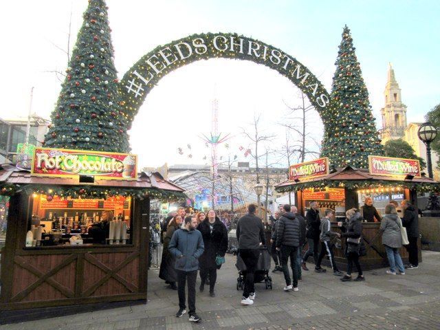 Leeds Christmas market, archway with lights, festive stalls, people walking.