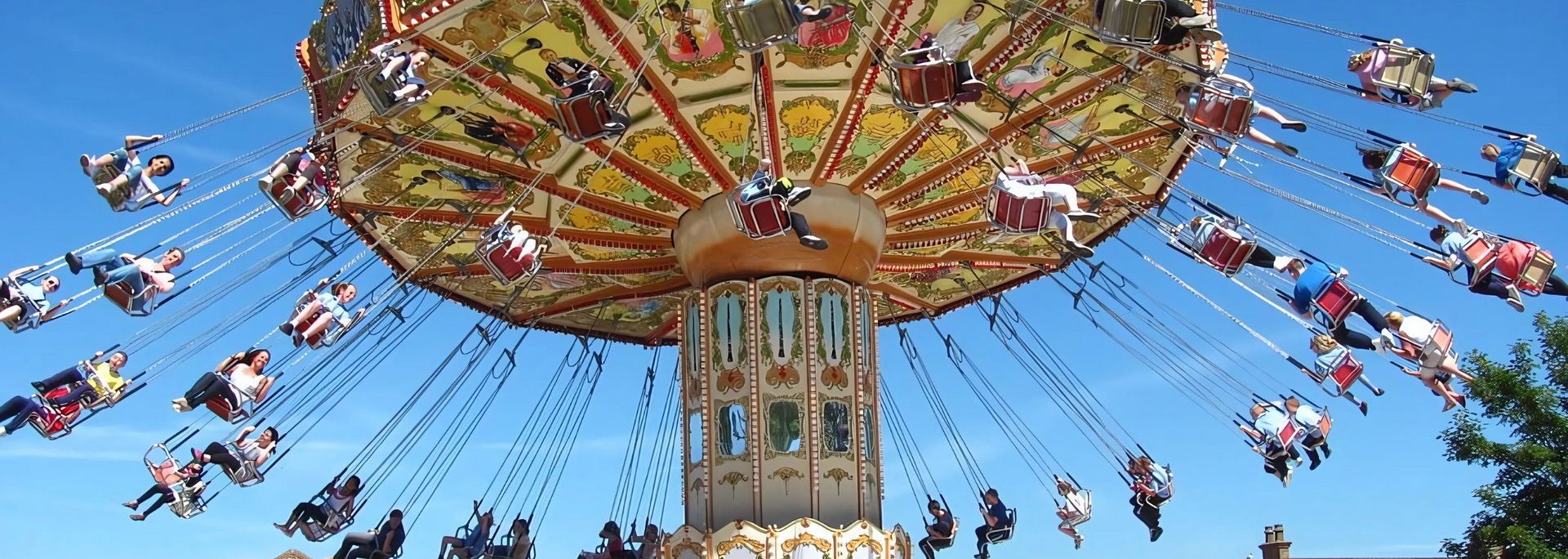 Carousel swing ride against a bright blue sky.