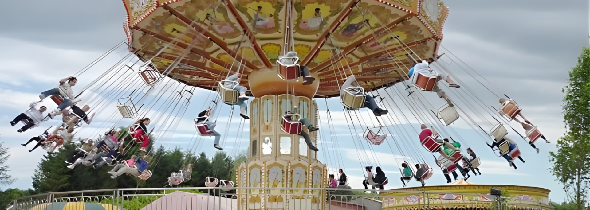 A carousel ride with people swinging in the air, against a cloudy sky.