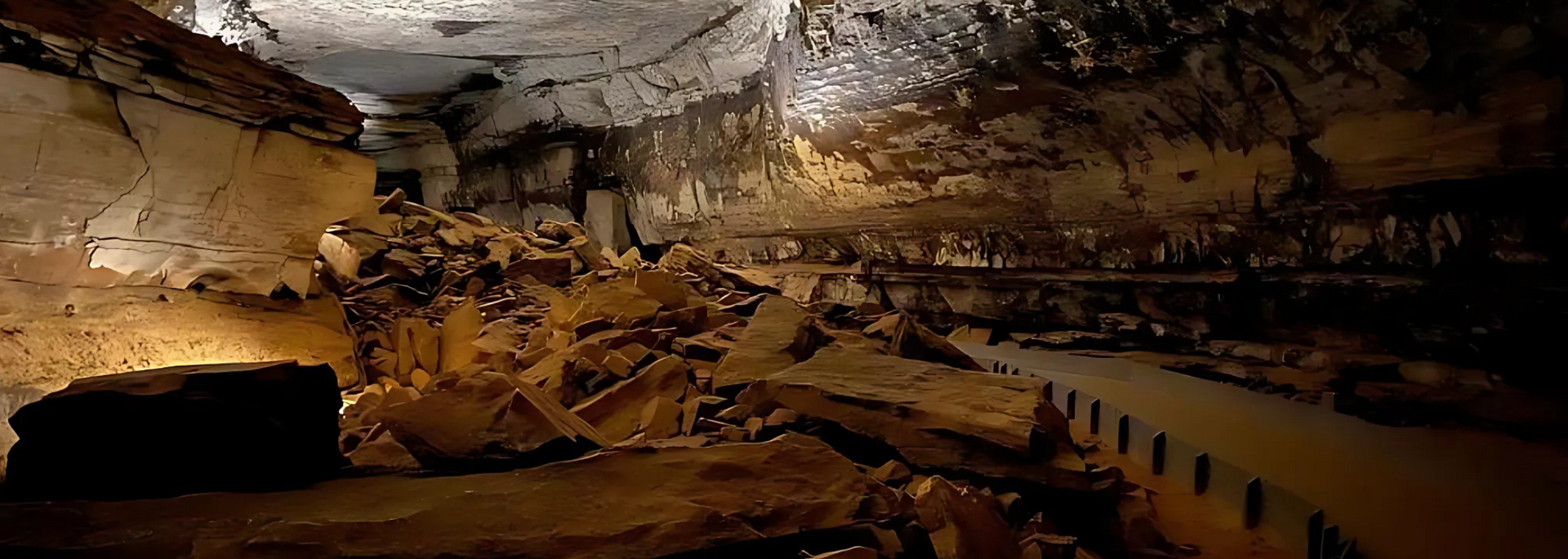 A cave interior with a pathway.  Jagged rock formations are illuminated by light.