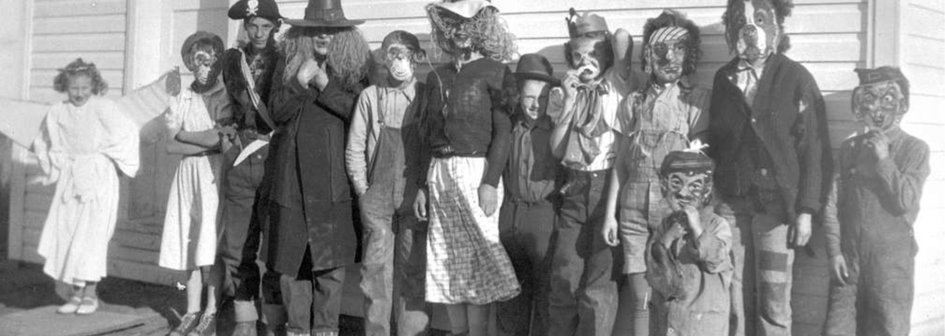 Group of people in costumes and masks posing outside.