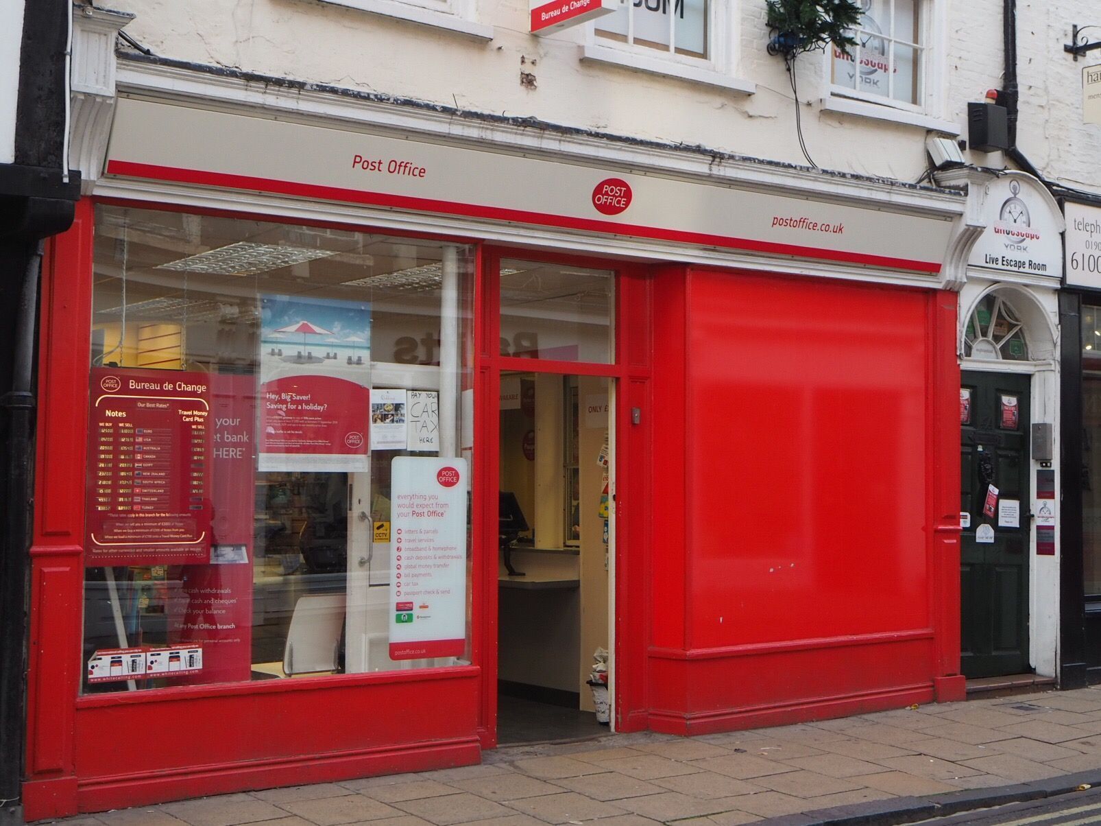 Red post office storefront with a glass window and doorway.