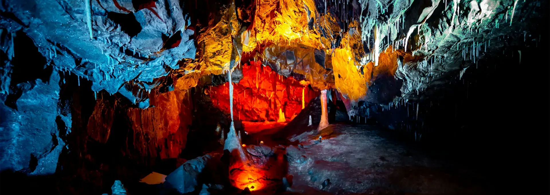 A brightly lit cave with colorful rock formations and stalactites.