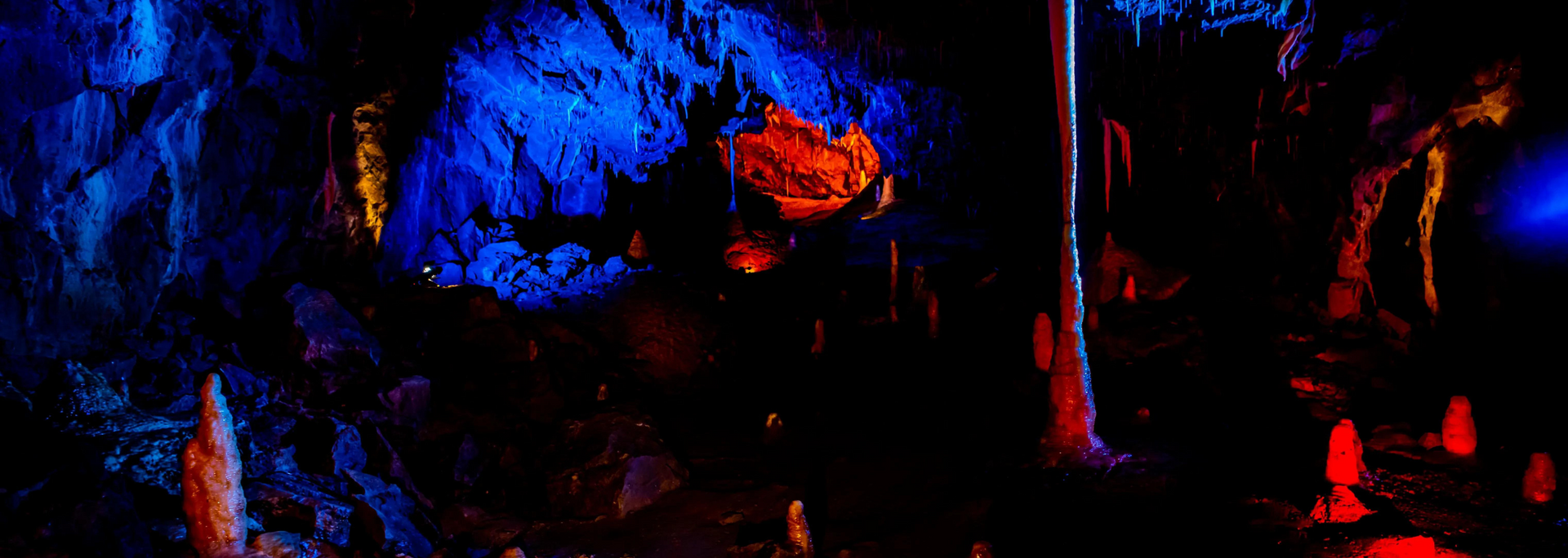 Cave interior with blue and red lighting illuminating rock formations.