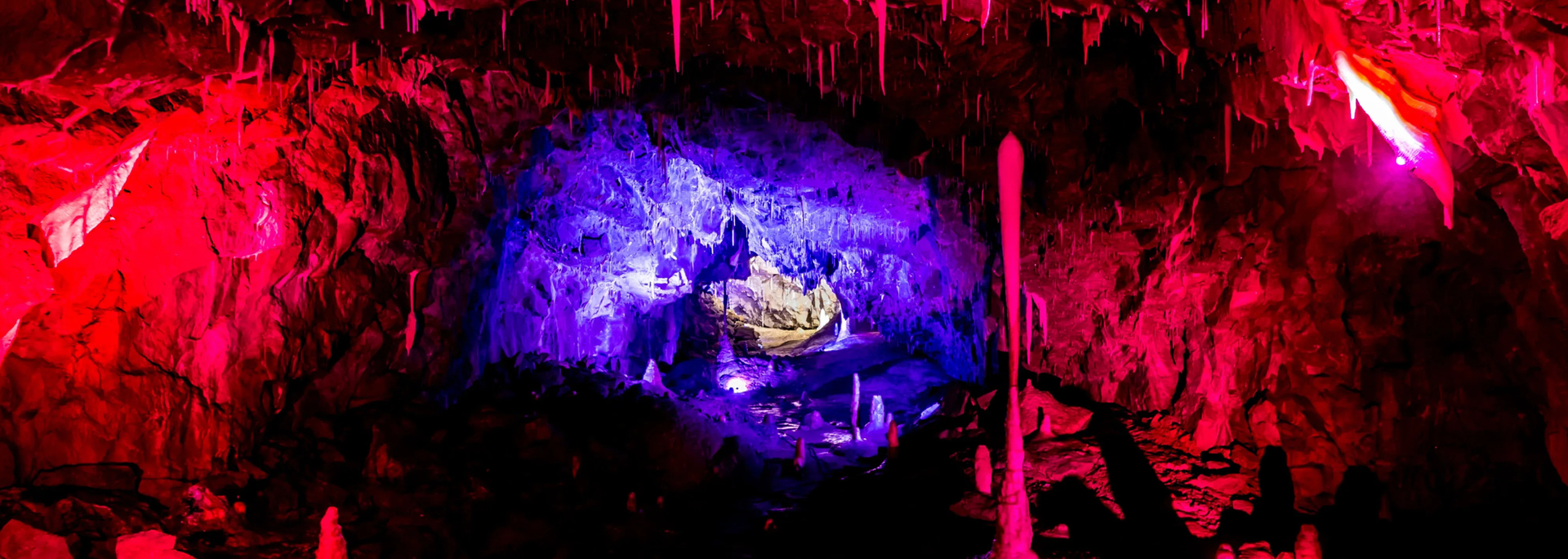 A cave bathed in red and purple light, with a glowing blue center.