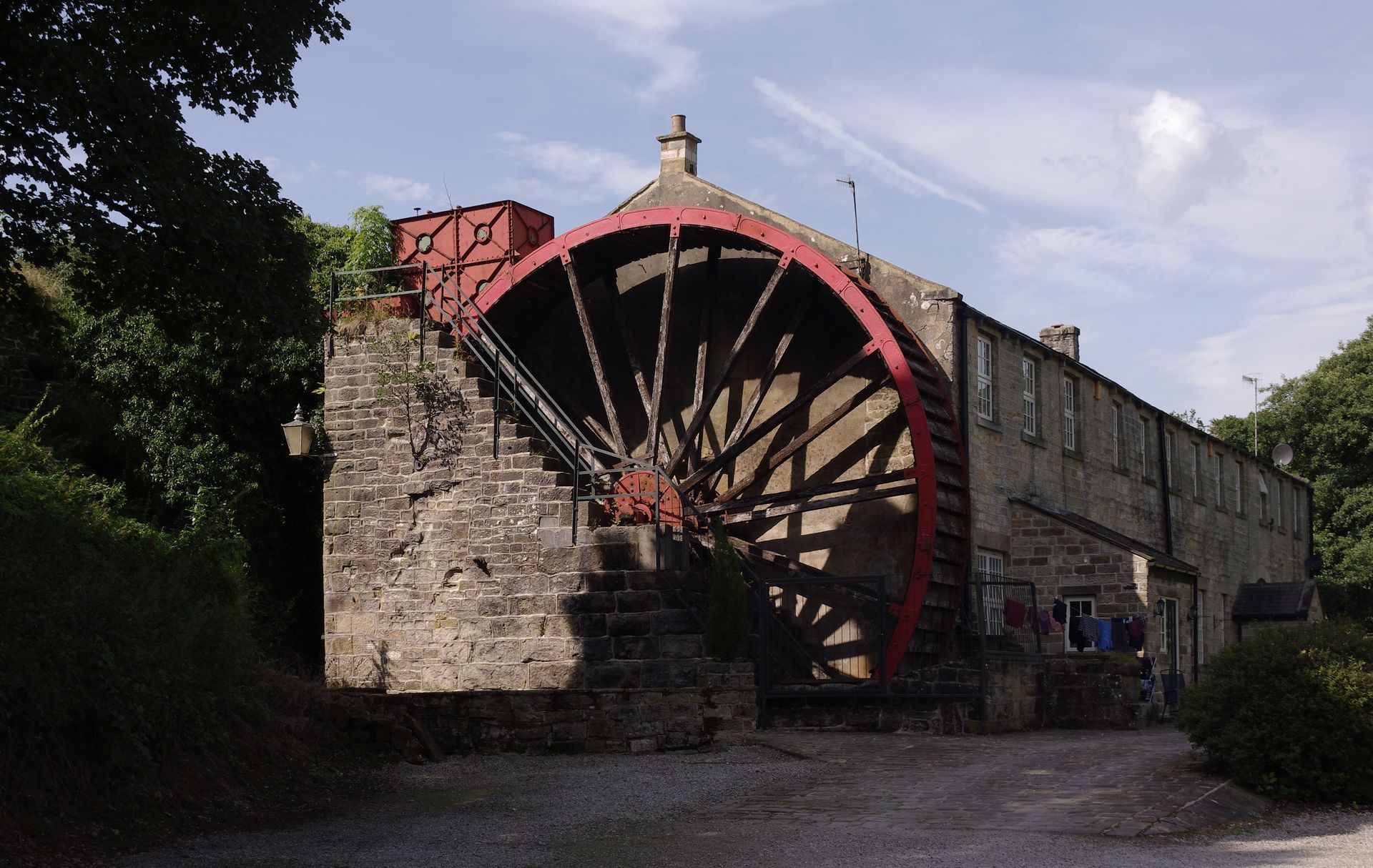 Stone mill building with a large red water wheel.