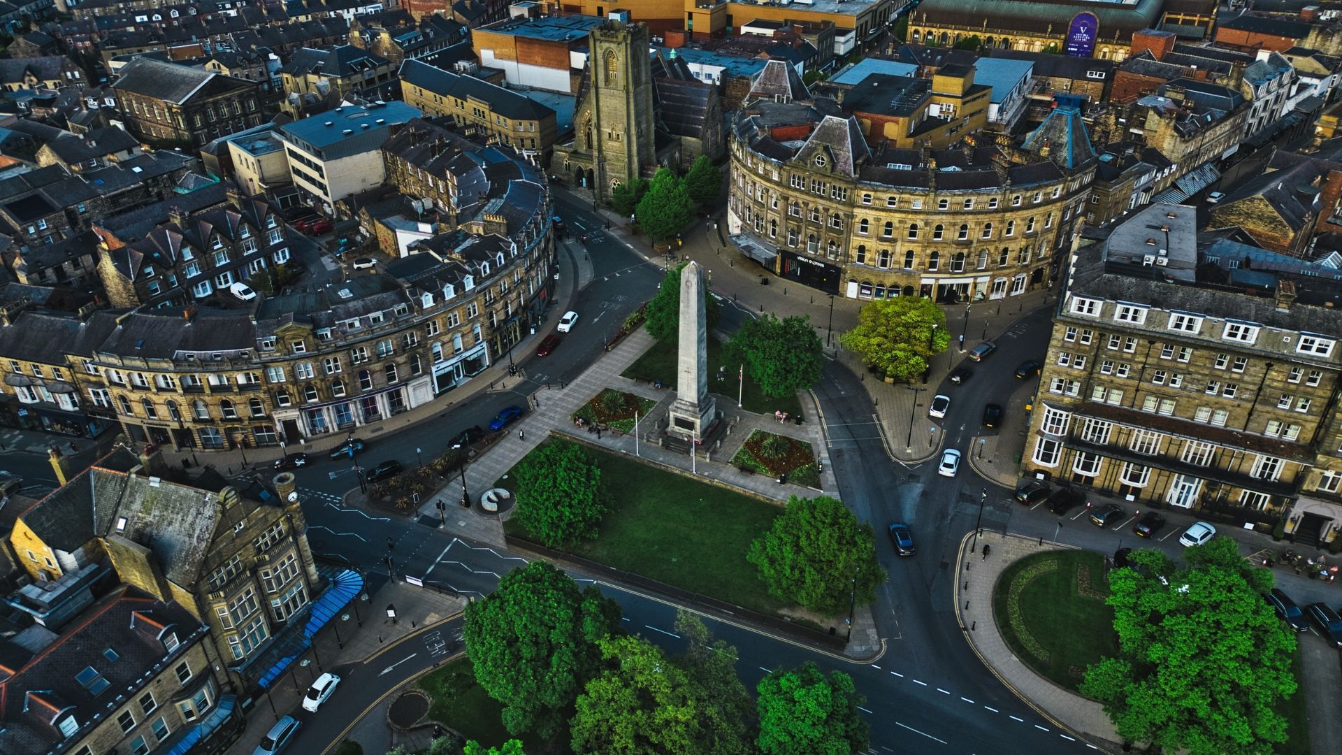 Aerial view of a city square with a tall obelisk surrounded by buildings and streets.