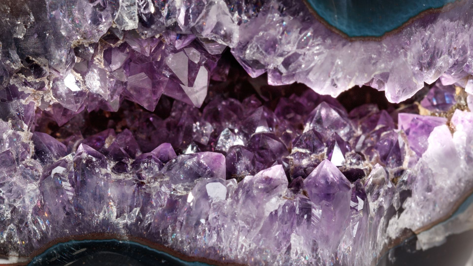 Purple amethyst crystals inside a geode, with a dark, rock-like border.