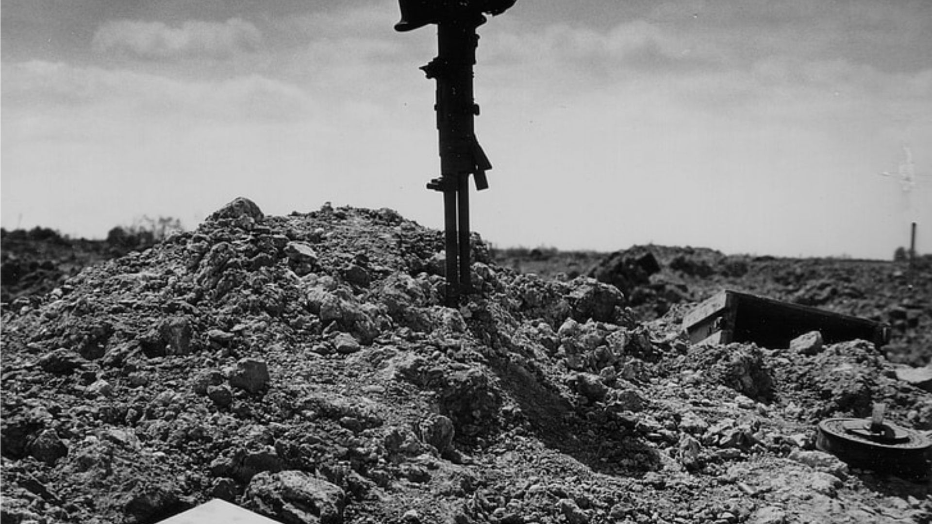 Heap of rubble with a rusty metal object in the middle, under a hazy sky.