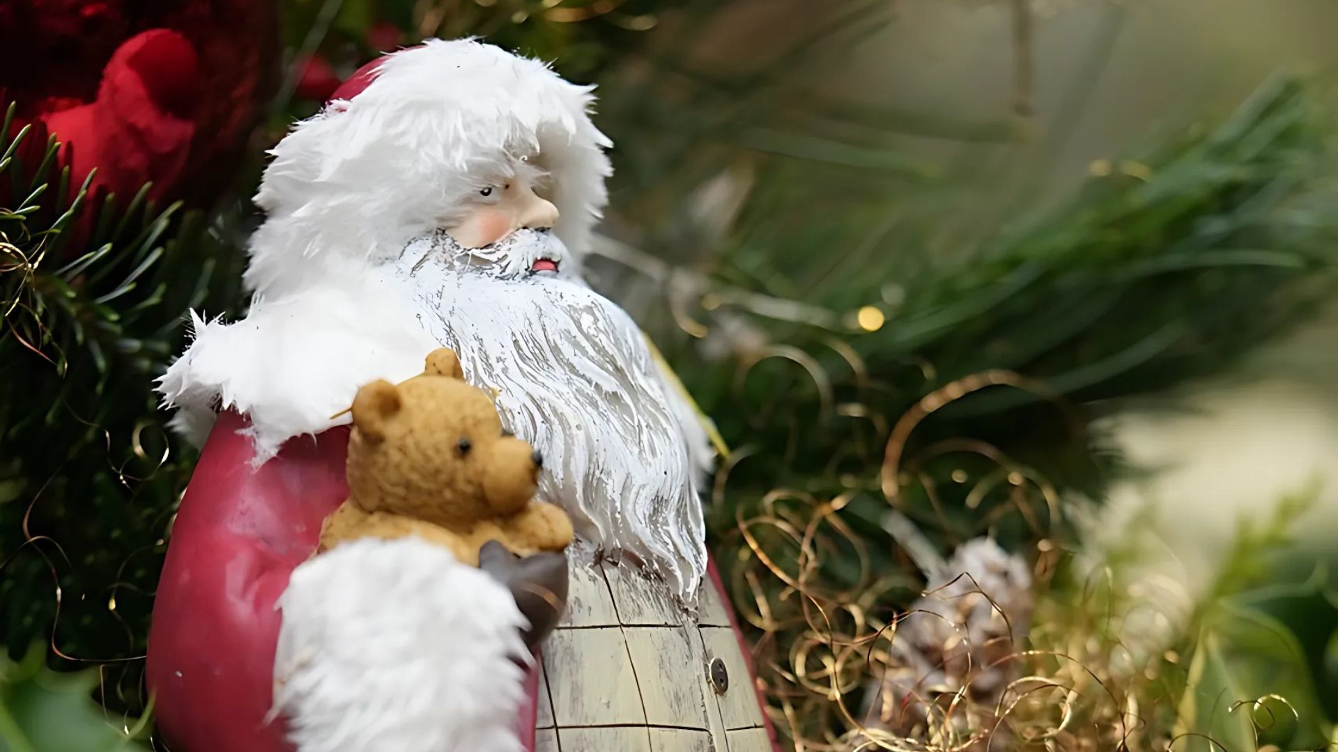 Santa Claus figurine holding a teddy bear, festive holiday decoration.