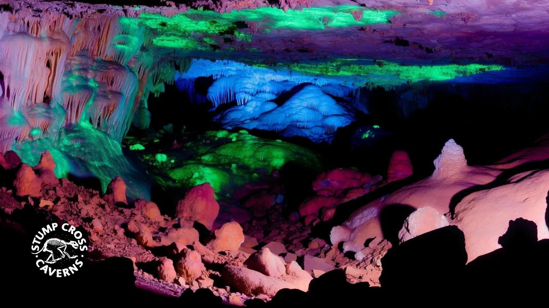 A colorful cave interior with illuminated rock formations in shades of green, blue, and purple.