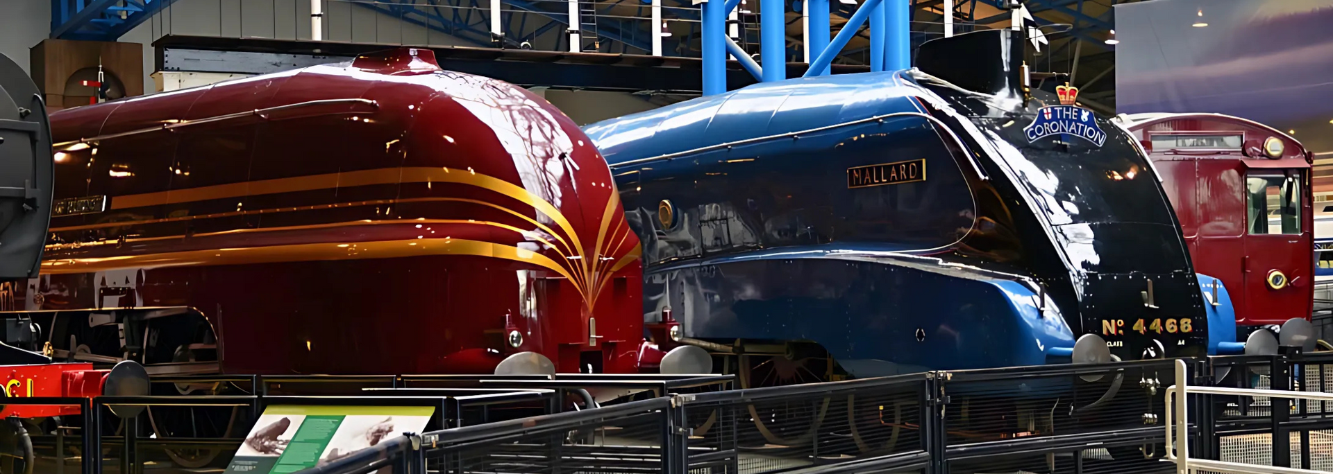 Steam locomotives and a red train car on display.