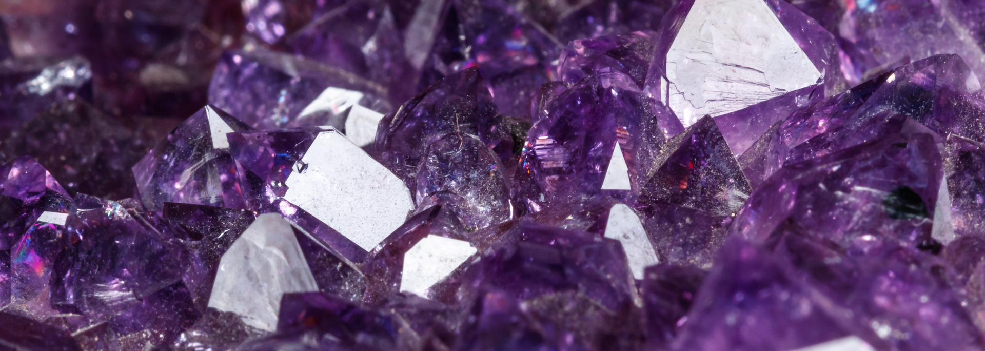 Close-up of sparkling, deep purple amethyst crystals with some white inclusions.
