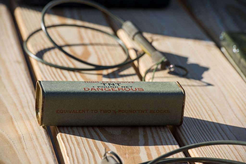 Box of detonators and blasting cap with connecting wire on a wooden surface.