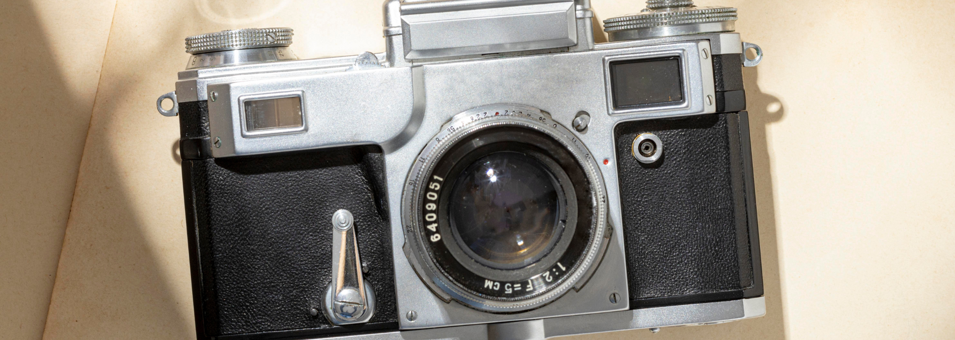 Silver and black vintage camera on a beige surface.