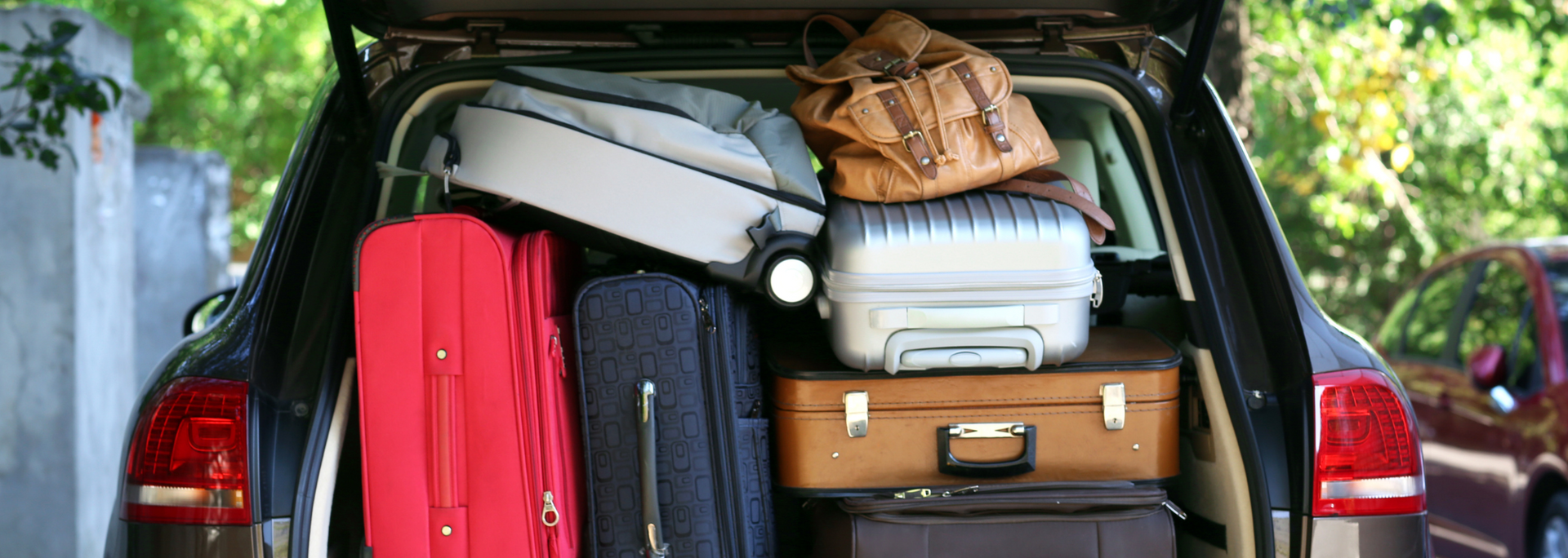 Open car trunk packed with multiple suitcases and bags; ready for travel.