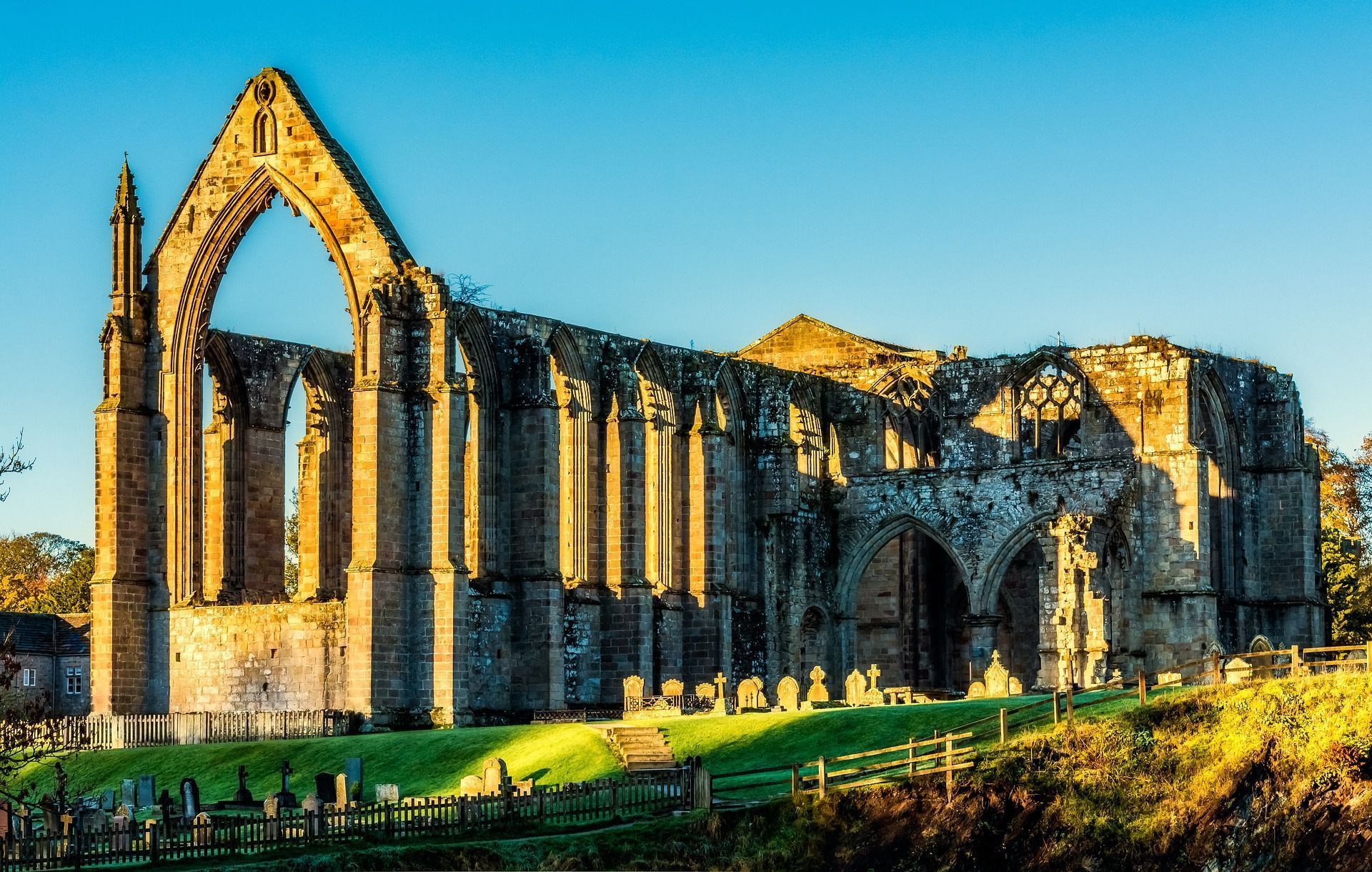 Ruined stone abbey under a bright blue sky, with arches and sunlight.