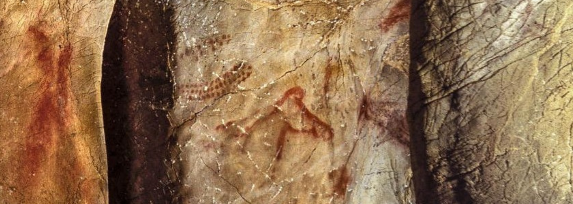 Cave painting of a bison-like figure in red ochre on a beige cave wall.