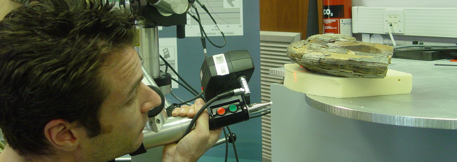 A person scanning a rock sample on a rotating surface with a handheld device.