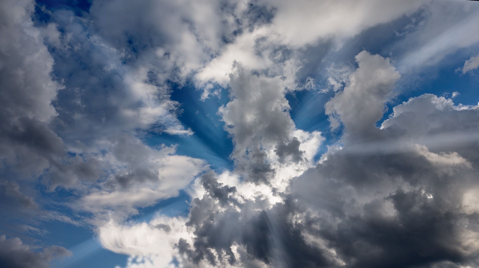 Dramatic clouds, mostly gray, with bright blue sky peeking through; sun rays.
