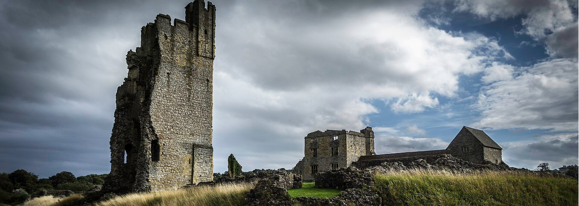 Stone ruins of a medieval castle under a cloudy sky.