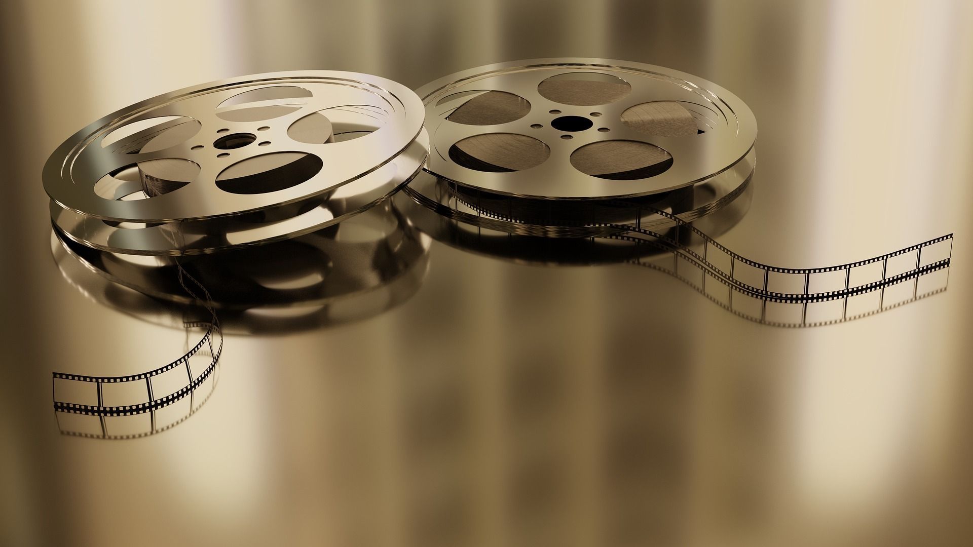 Two metallic film reels with film strip partially unspooled against a golden background.
