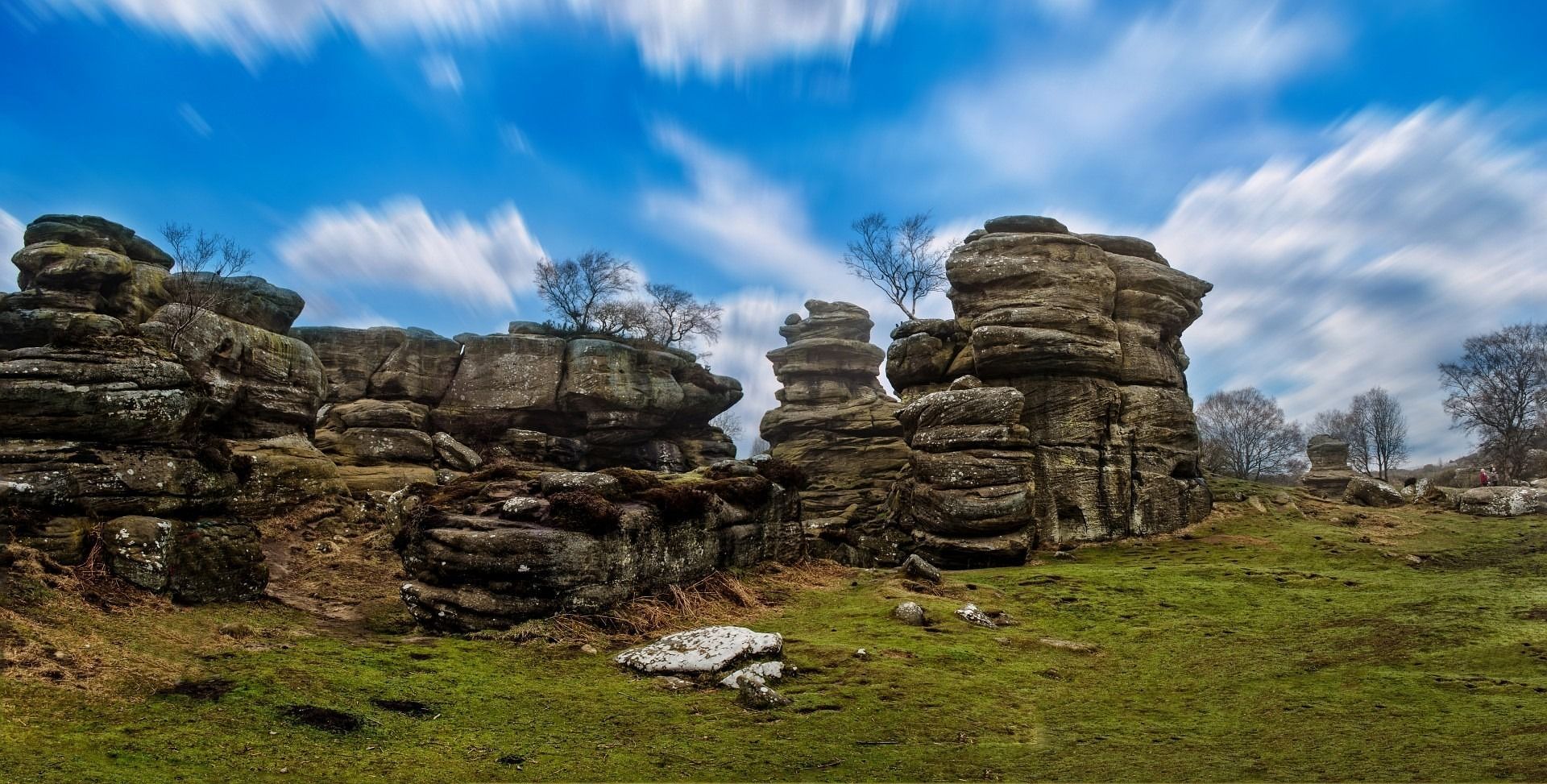 Rocky formations on a grassy plain under a partly cloudy blue sky.