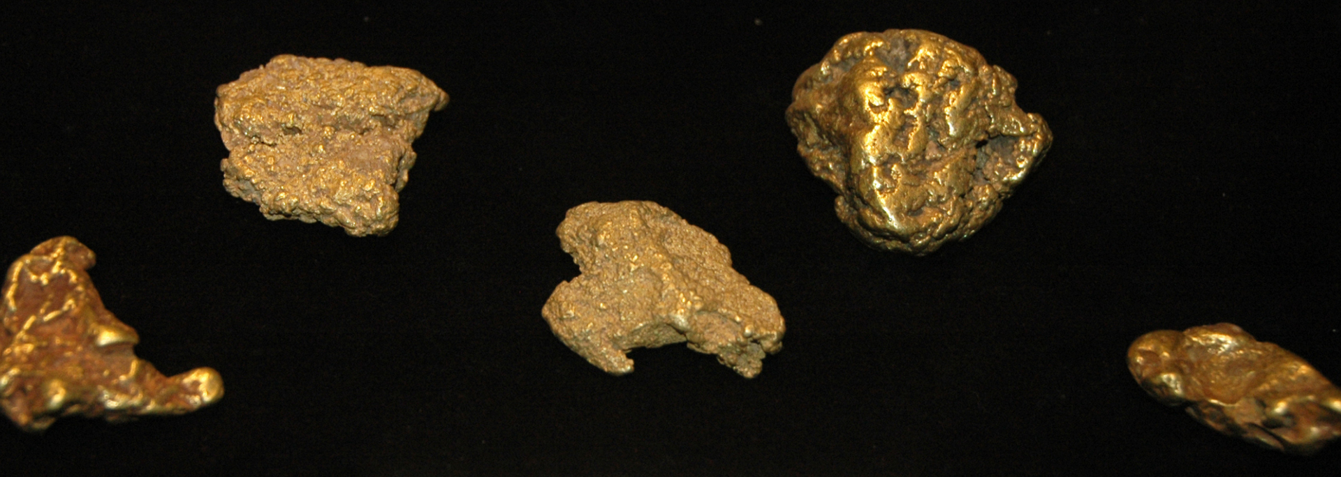 Five gold nuggets on a black background.