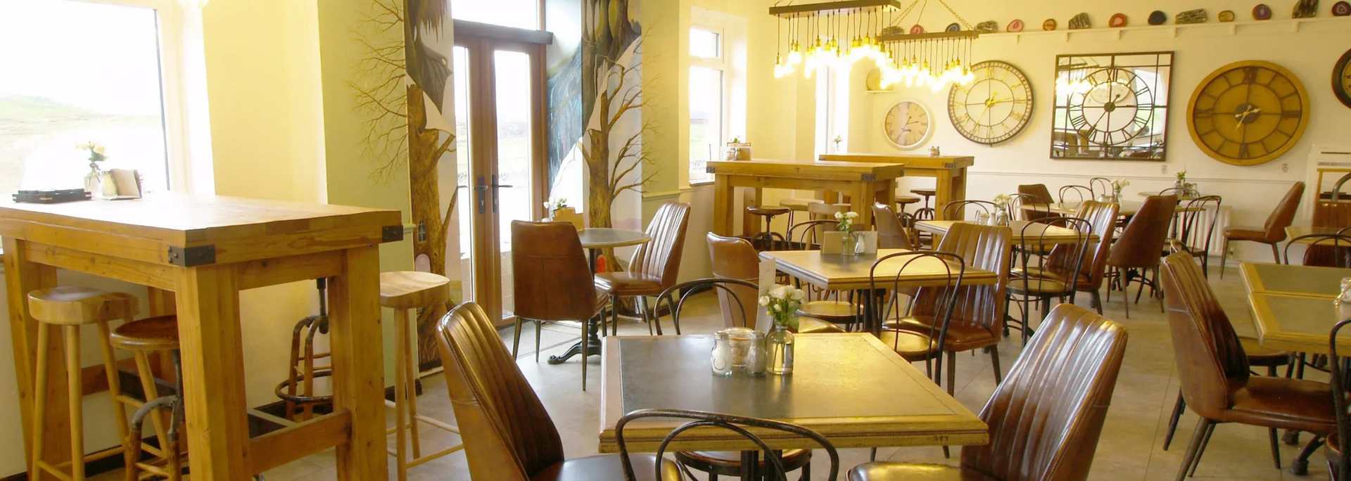Cafe interior with wooden tables, chairs, and large clocks on the wall.