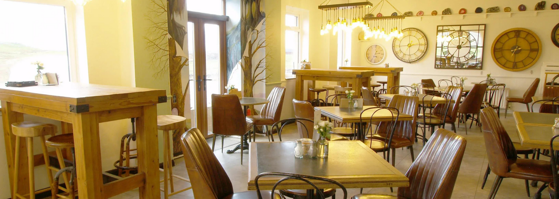 Interior of a cafe with wooden tables, chairs, and decorative clocks on the wall.
