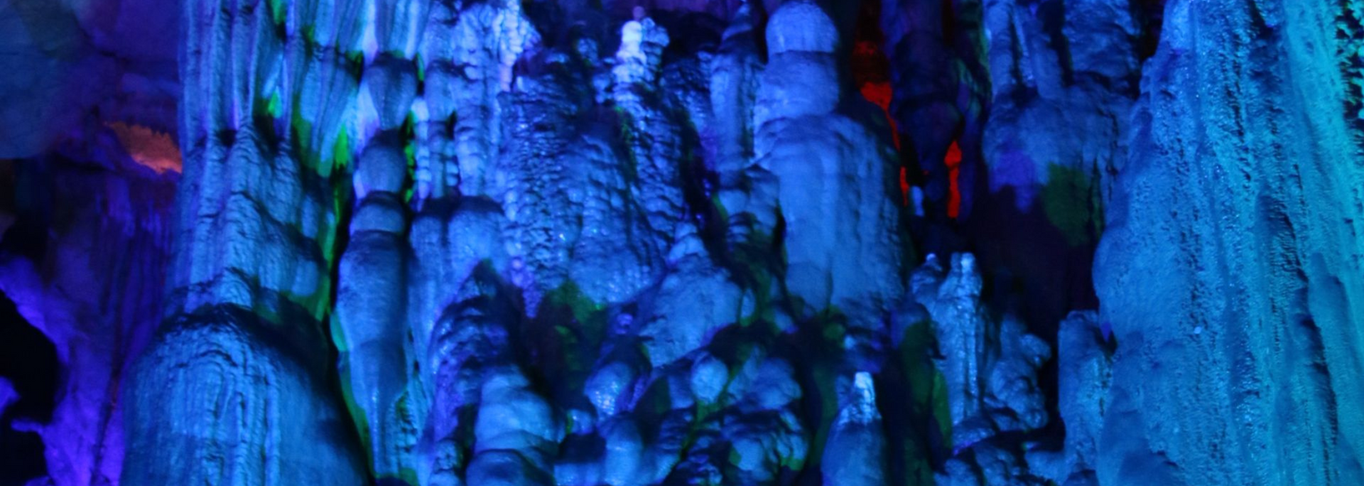 Cave formations illuminated with blue and green lights.