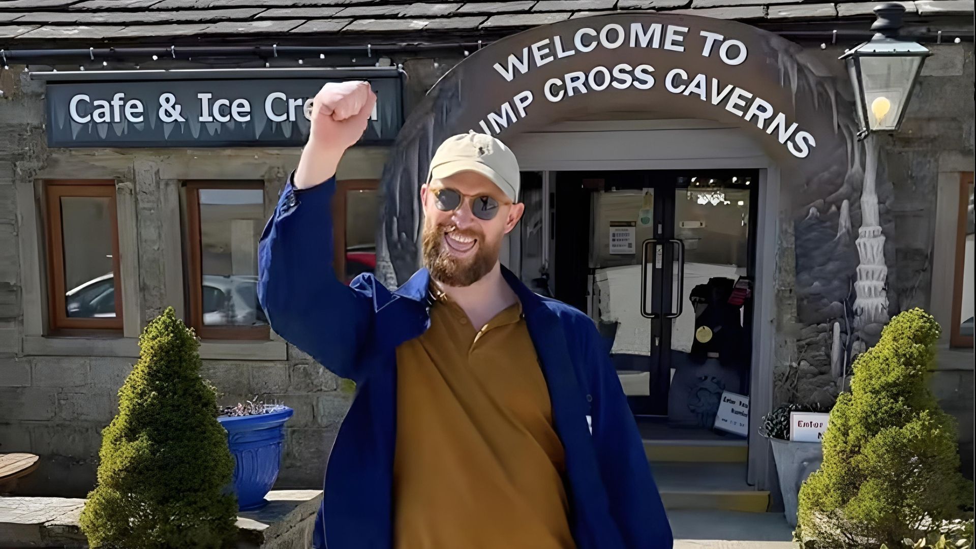 Man outside a cafe with raised fist, celebrating. Cafe entrance has a sign that reads 