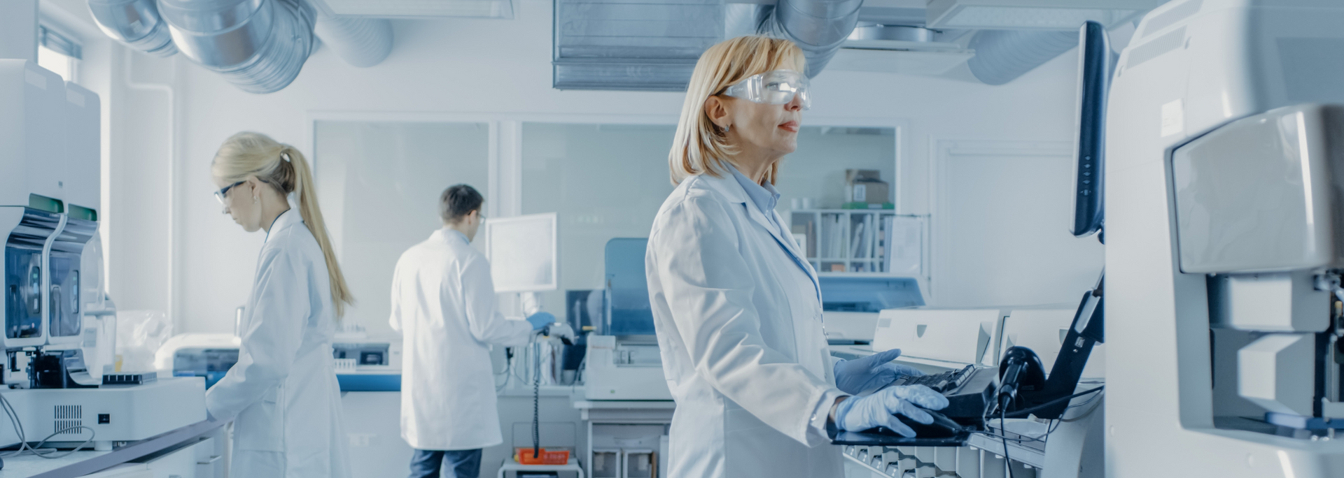 Scientists in lab coats working in a laboratory with complex equipment.