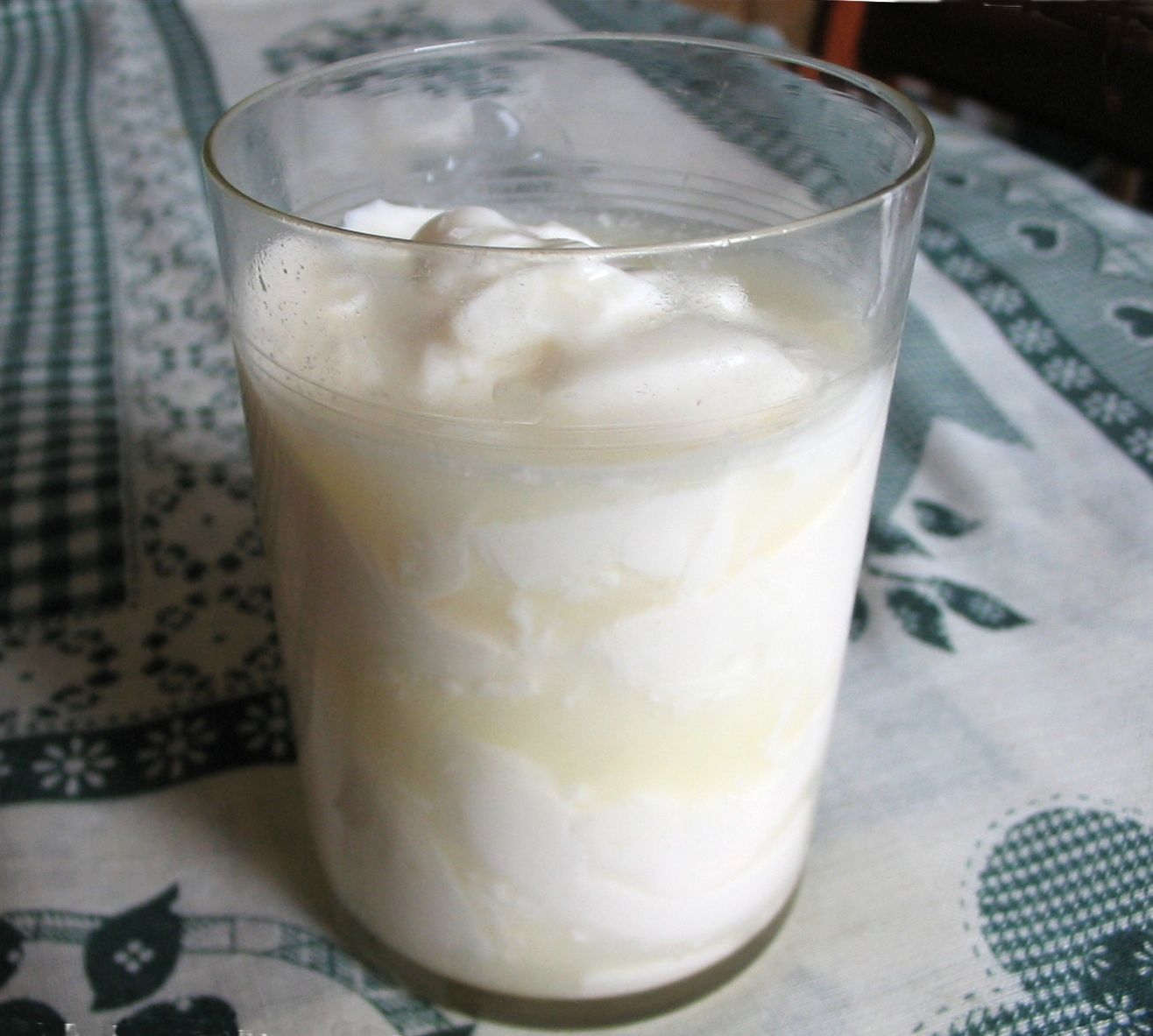 Glass of yogurt with a creamy, white texture; some liquid at the bottom.
