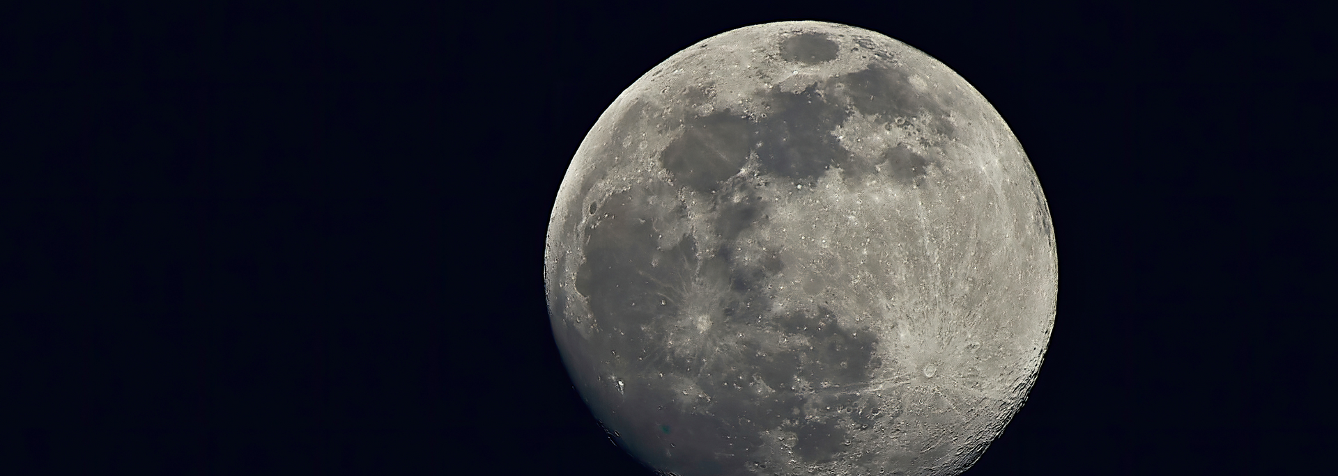 The moon against a dark blue night sky, showing craters and texture on its surface.