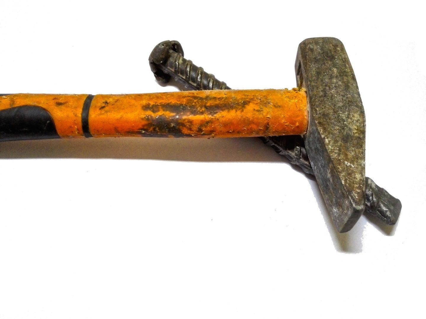 Hammer on a white surface, with a bent nail. Orange handle, gray head.