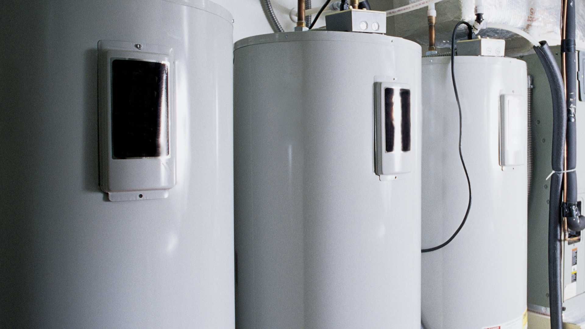 three white water heaters are lined up in a room .