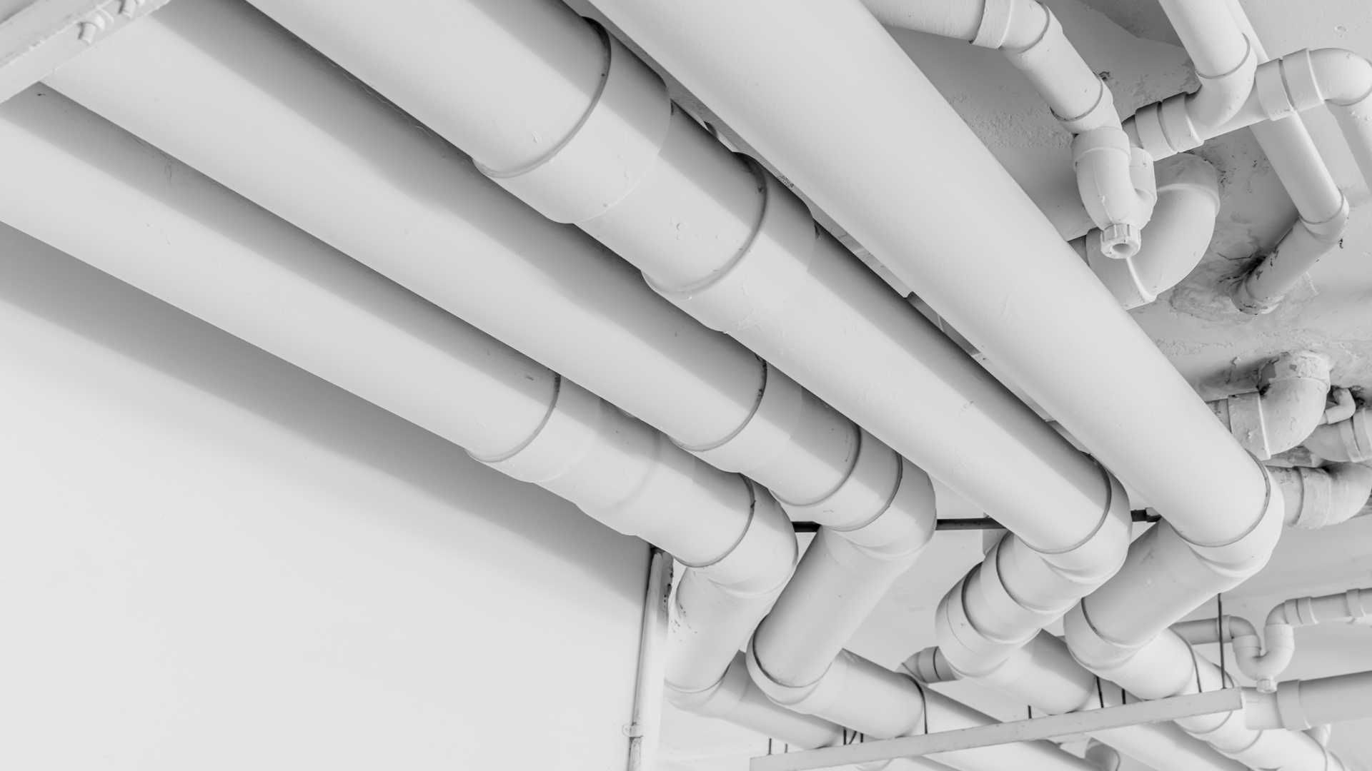 a row of white pipes hanging from the ceiling of a building .
