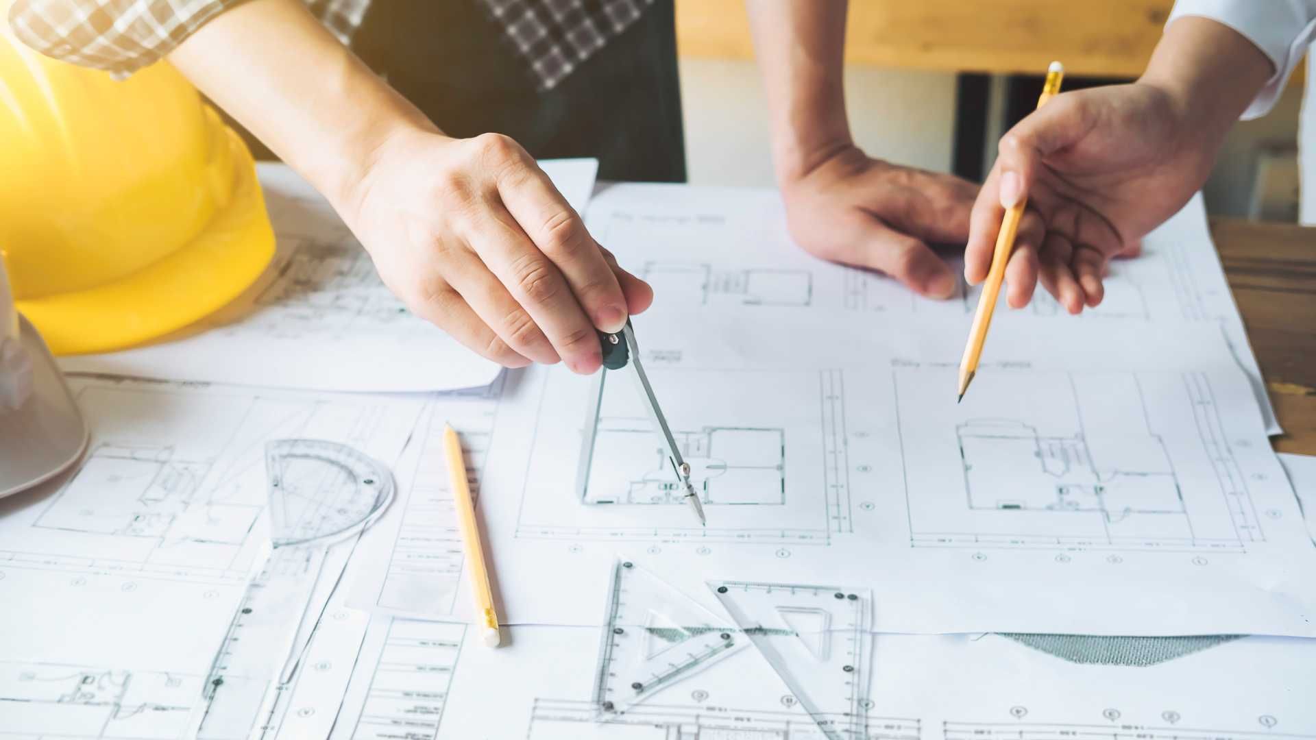 a group of people are sitting at a table looking at a blueprint .