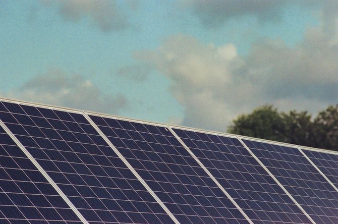Solar panels in the foreground beneath a blue sky with scattered clouds.