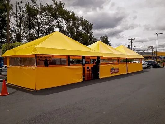 Carpas amarillas para eventos al aire libre instaladas a lo largo de una carretera bajo un cielo nublado.