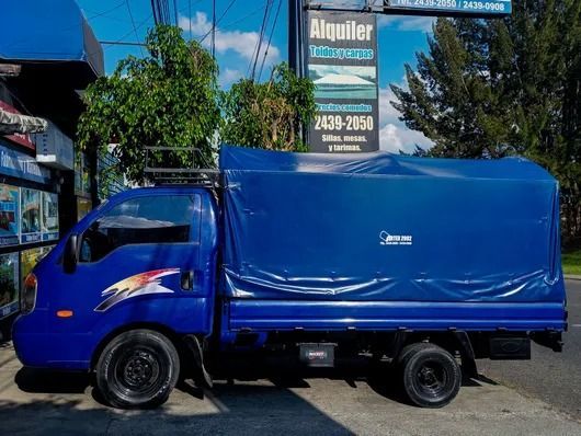 Camión de carga azul estacionado en una calle junto a un letrero de alquiler de 