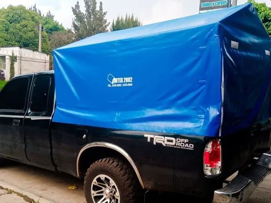 Camioneta negra con caja de carga cubierta de color azul estacionada al aire libre