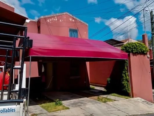 Dosel rosa sobre un camino de entrada junto a una casa de melocotones bajo un cielo azul