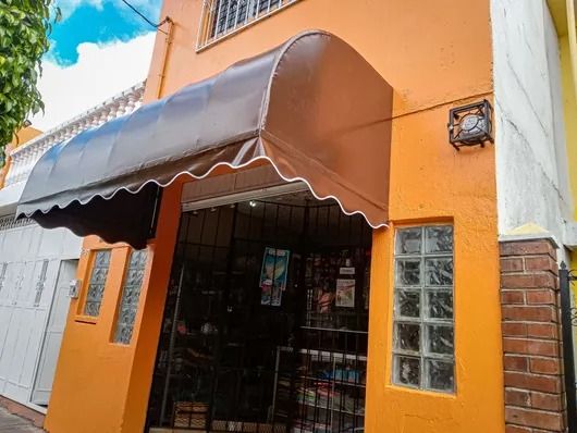 Fachada naranja con toldo marrón y puerta metálica en una esquina.