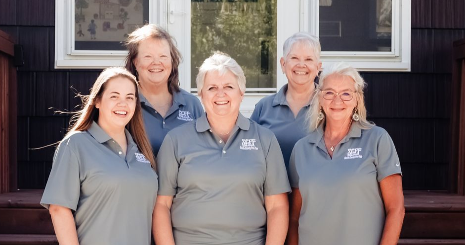 Group of six people in blue shirts posing outdoors.