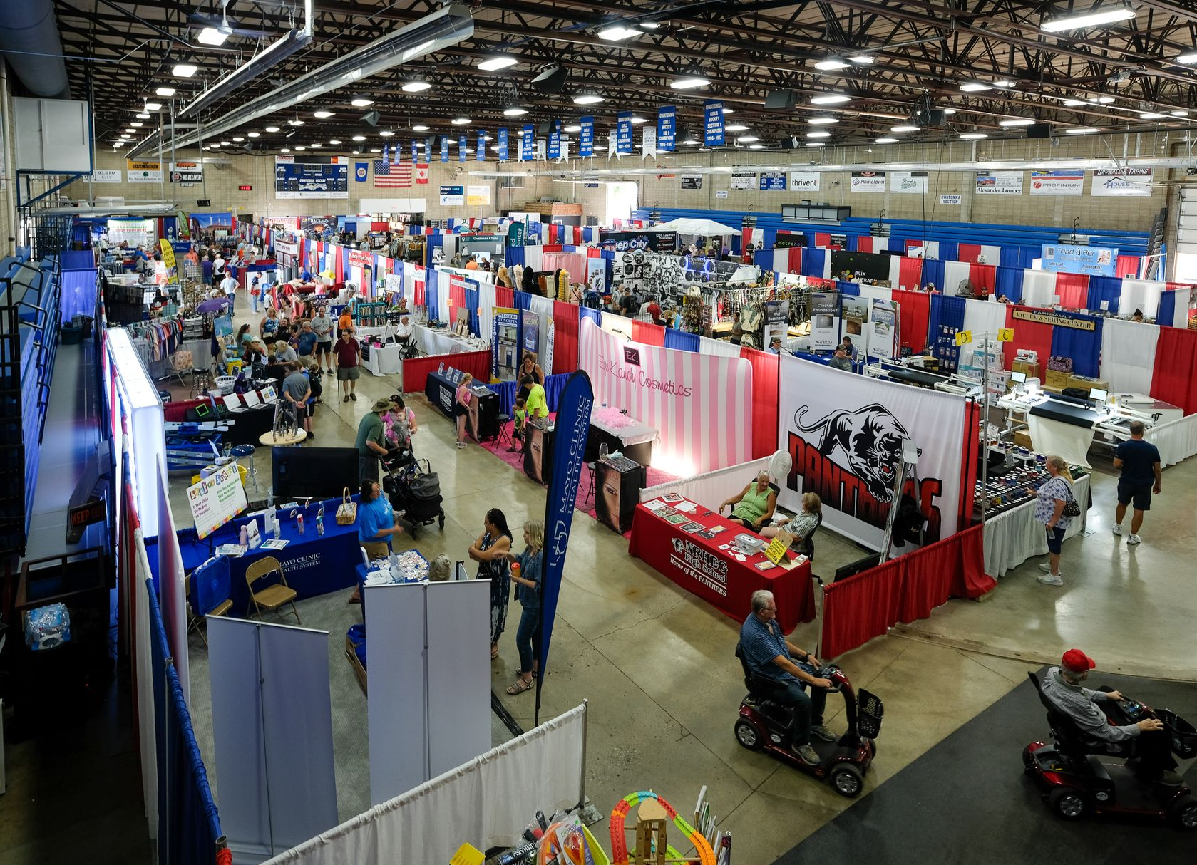 Large indoor event hall with vendor booths, attendees, and products on display.